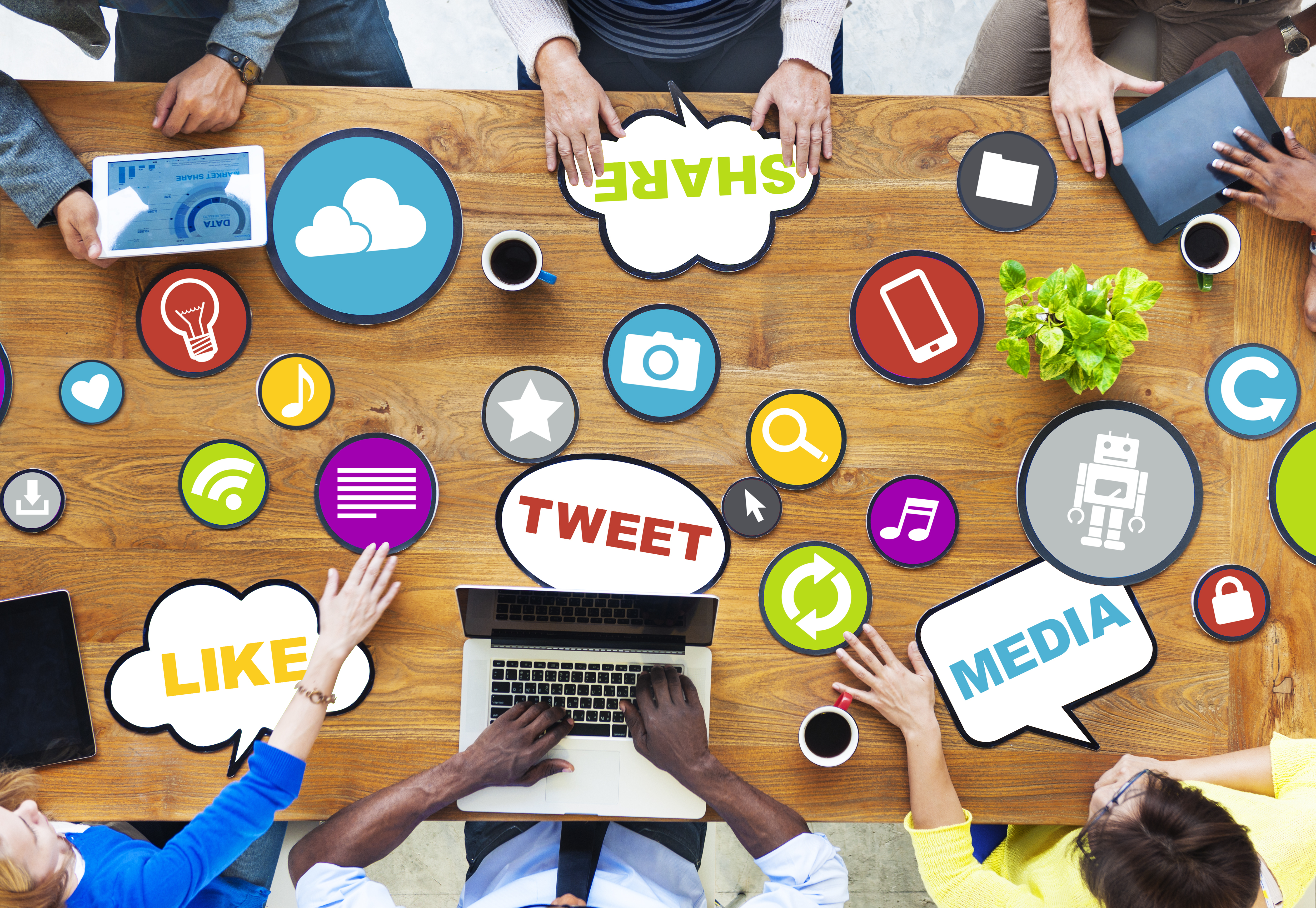 People sitting at conference table with social media icons on the desk